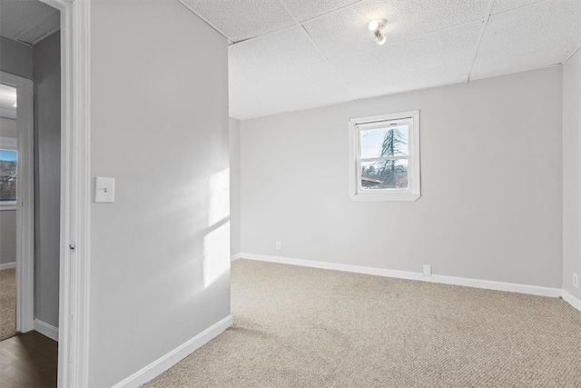 carpeted empty room featuring a paneled ceiling