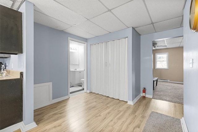 interior space featuring a baseboard radiator, light wood-type flooring, and a drop ceiling