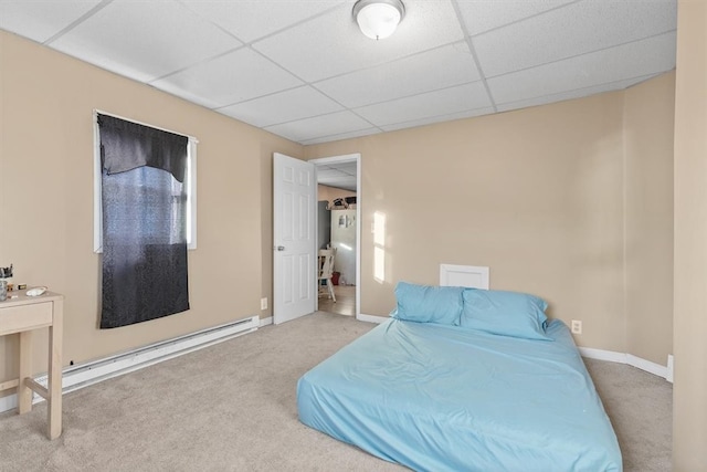 carpeted bedroom with a baseboard radiator and a paneled ceiling