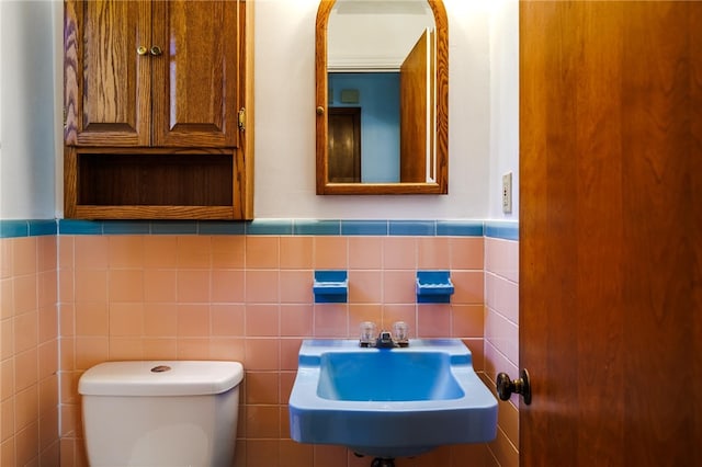 bathroom with tile walls, sink, and toilet