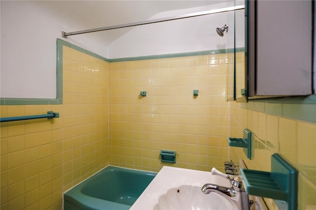 bathroom featuring tiled shower / bath combo, tile walls, and sink