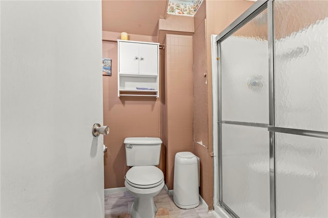 bathroom with tile patterned floors, toilet, tile walls, and walk in shower