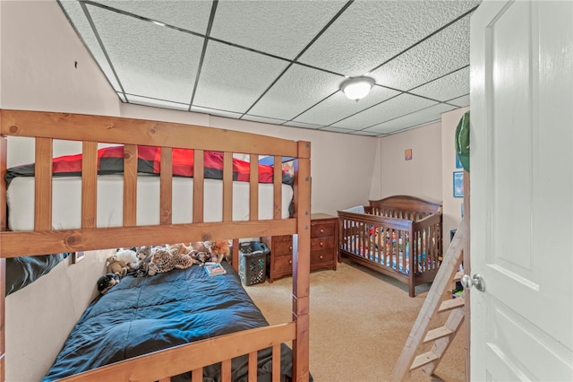 carpeted bedroom featuring a drop ceiling