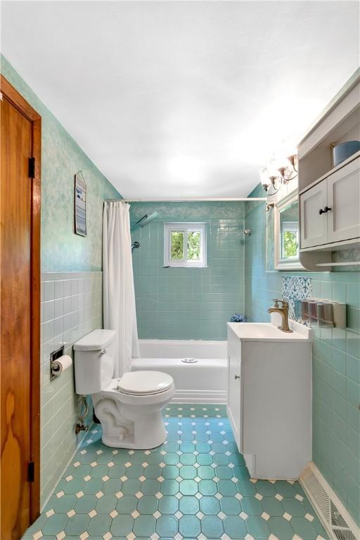 full bathroom with tile walls, vanity, a wealth of natural light, and shower / bath combination with curtain