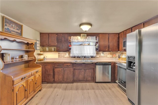 kitchen featuring appliances with stainless steel finishes, sink, tasteful backsplash, and light hardwood / wood-style flooring