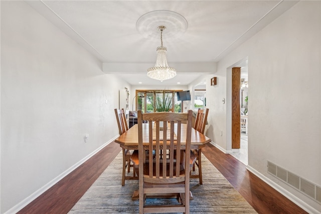 dining room with dark hardwood / wood-style floors and a chandelier