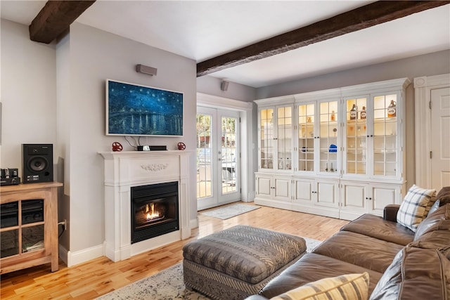 living room with french doors, light hardwood / wood-style floors, and beam ceiling