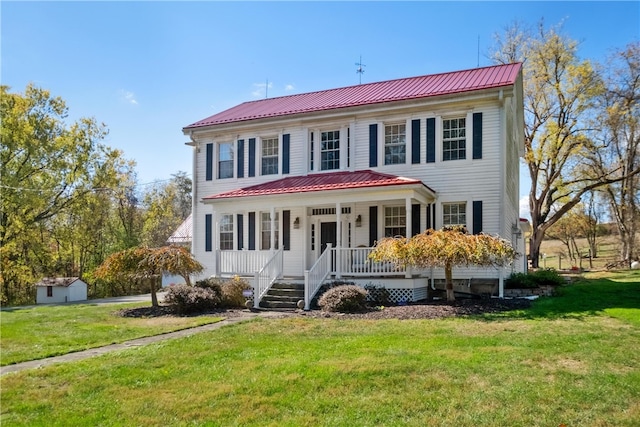 view of front facade featuring covered porch, a front yard, and a storage shed