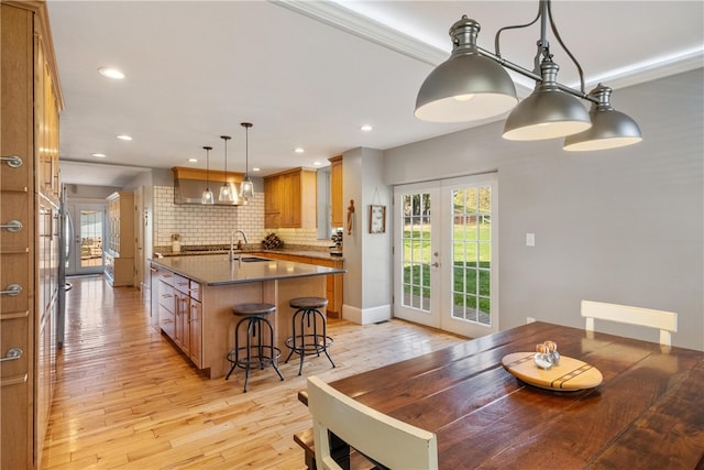 dining space featuring ornamental molding, sink, french doors, and light hardwood / wood-style floors