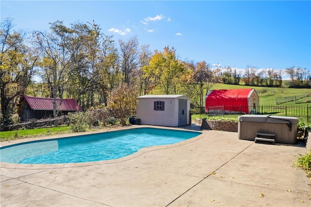 view of pool with a hot tub, a patio area, and a storage shed