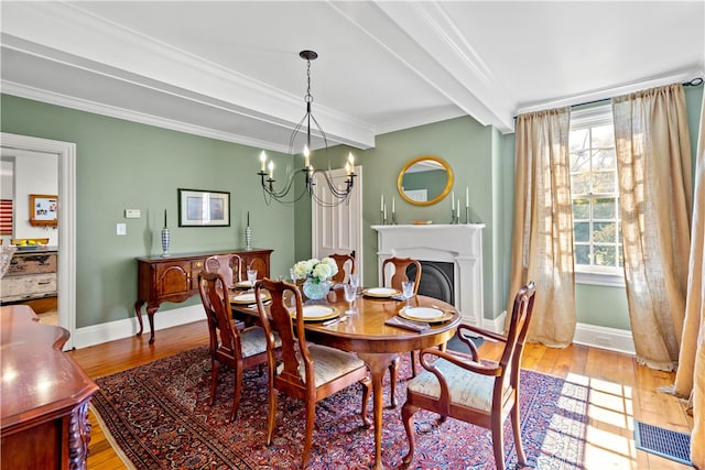 dining room featuring light hardwood / wood-style floors, beamed ceiling, crown molding, and an inviting chandelier