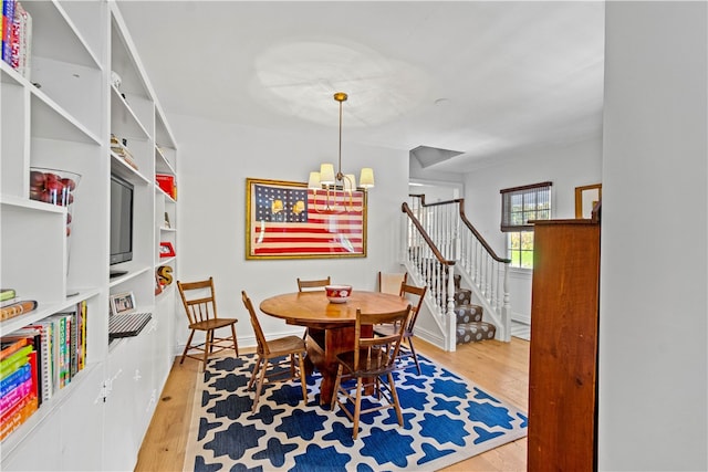 dining room with light hardwood / wood-style floors and a notable chandelier