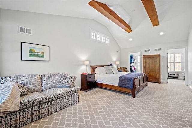 carpeted bedroom featuring beamed ceiling, multiple windows, a walk in closet, and high vaulted ceiling