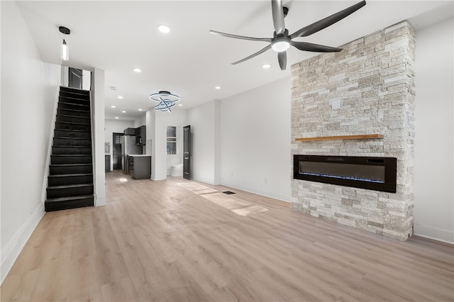 unfurnished living room featuring a fireplace, light hardwood / wood-style floors, and ceiling fan