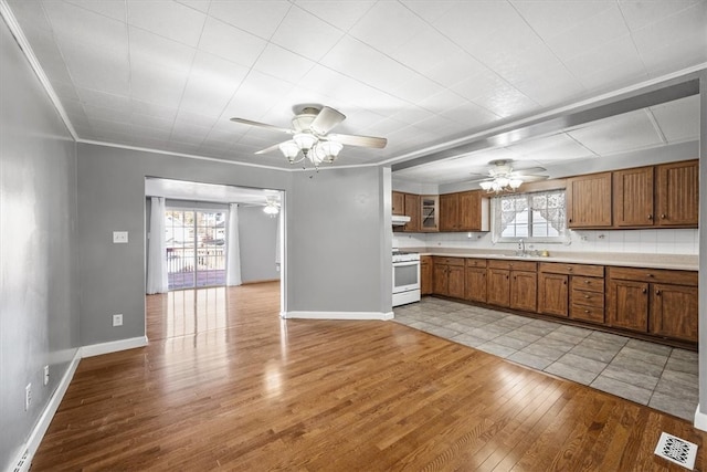 kitchen featuring light wood-type flooring, a wealth of natural light, white stove, and ornamental molding