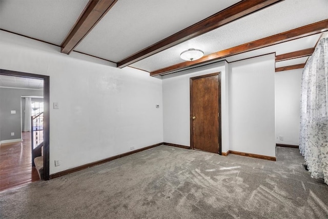 carpeted empty room with a textured ceiling and beam ceiling