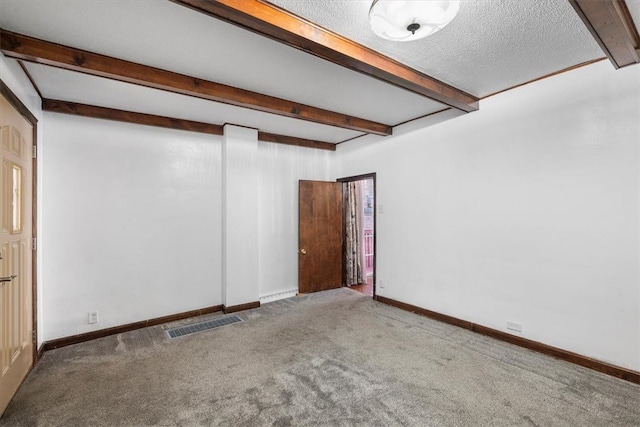 carpeted empty room featuring a textured ceiling and beam ceiling