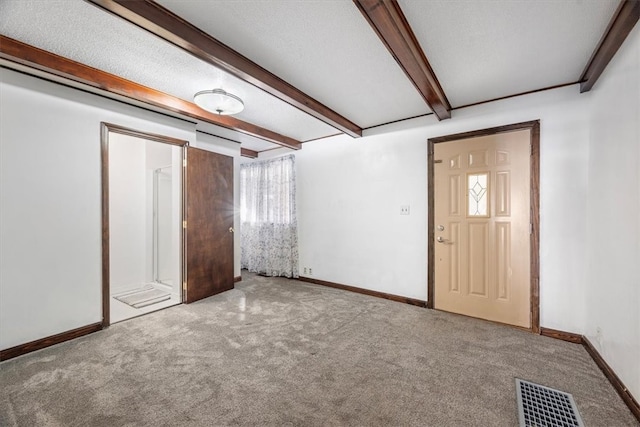 carpeted spare room with a textured ceiling and beam ceiling