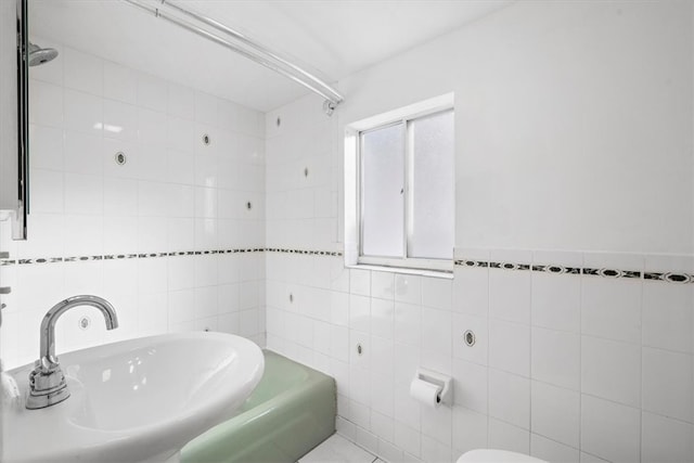 bathroom featuring tiled shower / bath, sink, and tile walls