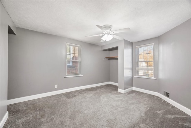 spare room featuring a textured ceiling, carpet flooring, and ceiling fan