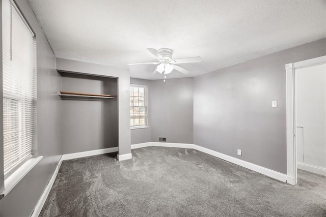 unfurnished bedroom featuring ceiling fan, dark colored carpet, a closet, and a textured ceiling