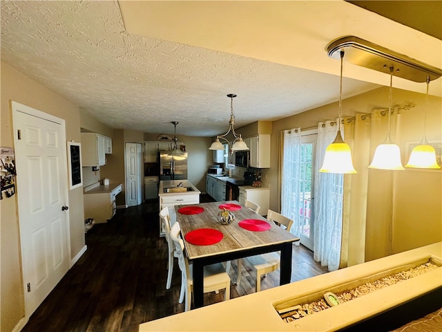 dining area with a textured ceiling and dark wood-type flooring