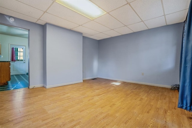 empty room featuring a paneled ceiling and light hardwood / wood-style flooring