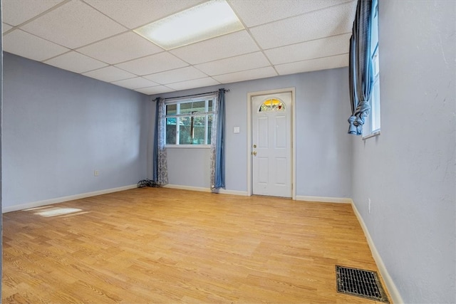 empty room with a paneled ceiling and light hardwood / wood-style flooring