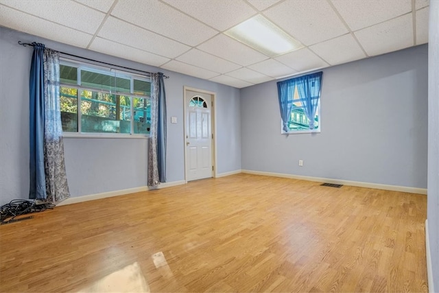 spare room featuring a paneled ceiling and light hardwood / wood-style floors