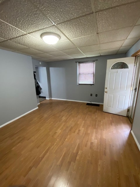 unfurnished room with a paneled ceiling and wood-type flooring