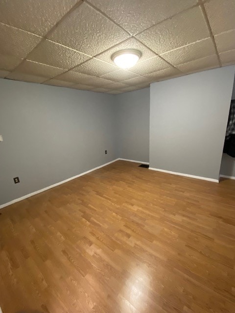 basement with hardwood / wood-style floors and a paneled ceiling