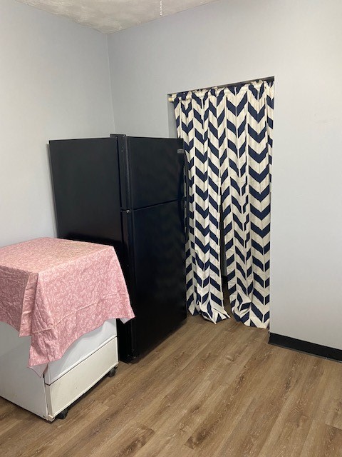 bedroom featuring black refrigerator, a textured ceiling, and light hardwood / wood-style flooring