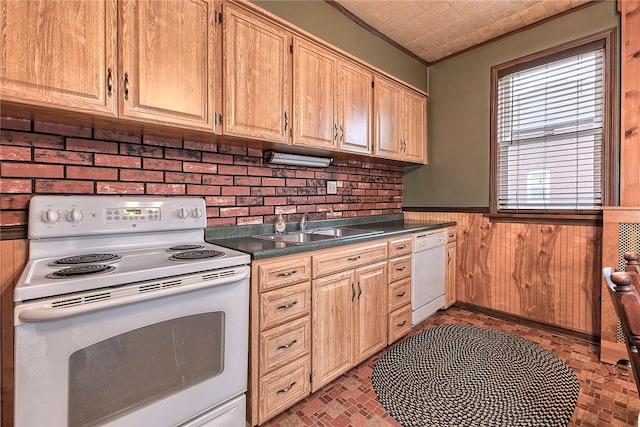 kitchen with wood walls, sink, ornamental molding, light brown cabinetry, and white appliances