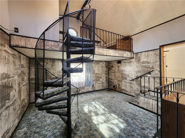 stairway featuring carpet flooring, a healthy amount of sunlight, and a towering ceiling