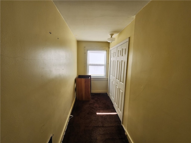 hall with dark colored carpet