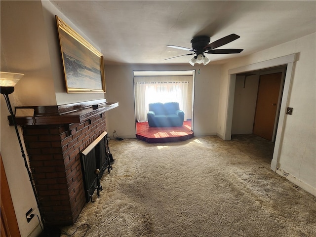 sitting room with a brick fireplace, carpet floors, and ceiling fan