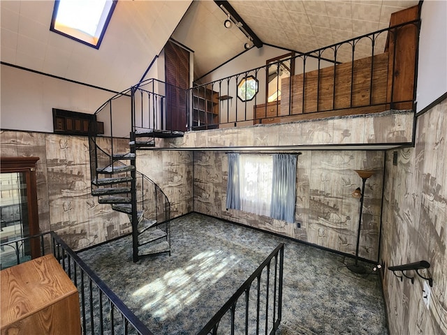 staircase featuring vaulted ceiling with skylight and rail lighting