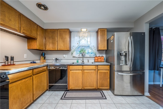 kitchen with light tile patterned flooring, sink, and black appliances