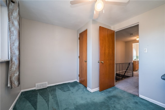 empty room featuring ceiling fan and dark carpet