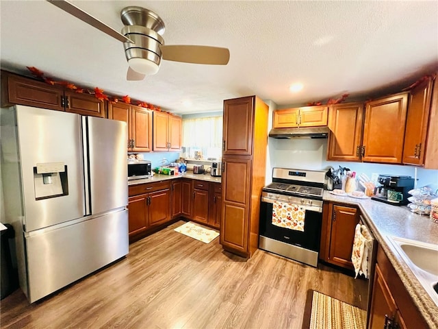 kitchen featuring stainless steel appliances, a textured ceiling, sink, ceiling fan, and light hardwood / wood-style flooring