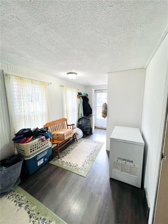 bedroom featuring dark hardwood / wood-style flooring, refrigerator, and a textured ceiling