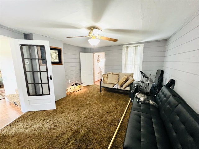 carpeted living room with wood walls and ceiling fan