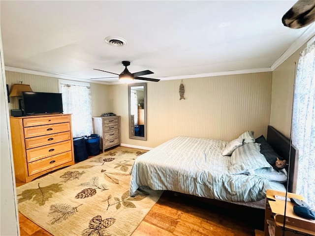 bedroom with hardwood / wood-style flooring, ceiling fan, and ornamental molding