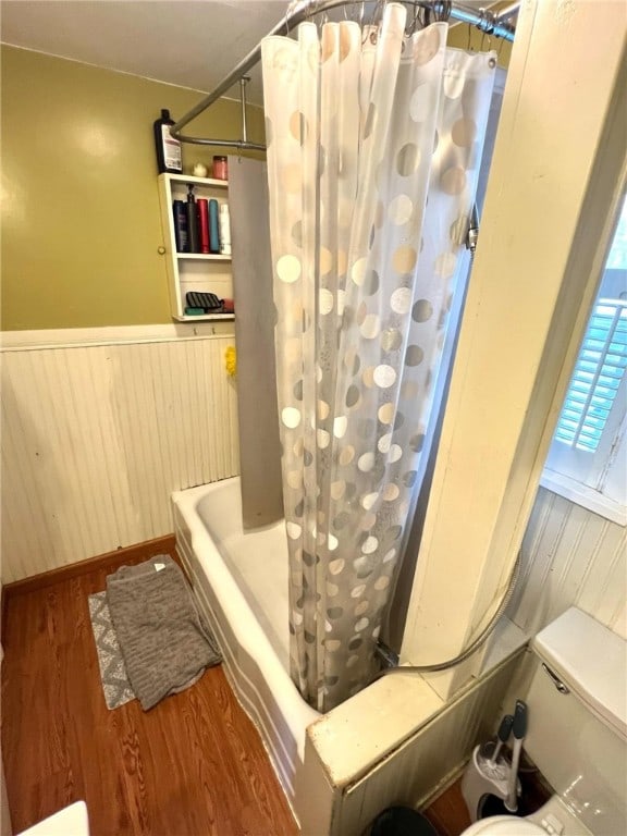 bathroom featuring shower / bath combo, wooden walls, and hardwood / wood-style floors