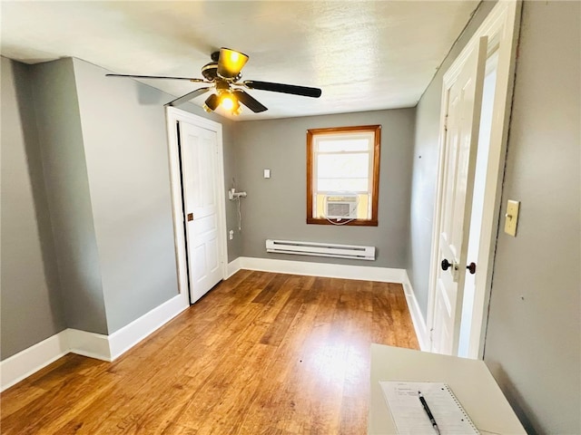 unfurnished room featuring ceiling fan, baseboard heating, cooling unit, and light wood-type flooring