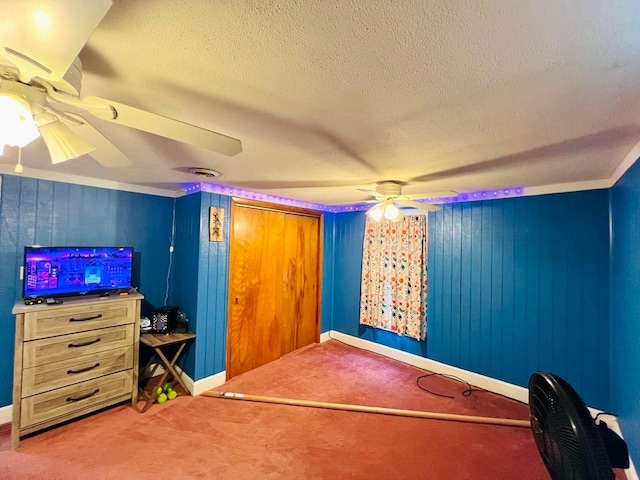 interior space featuring carpet flooring, a textured ceiling, wooden walls, and ceiling fan