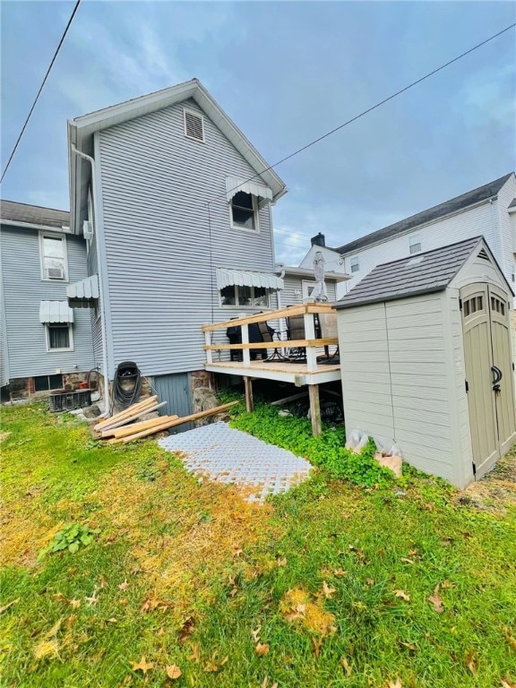 back of house with a storage shed and a lawn