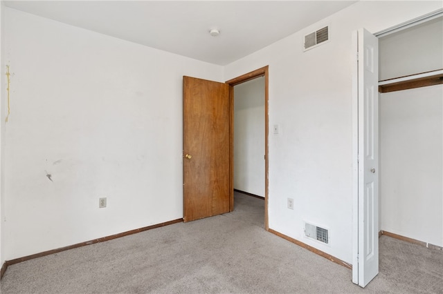 unfurnished bedroom featuring light carpet and a closet