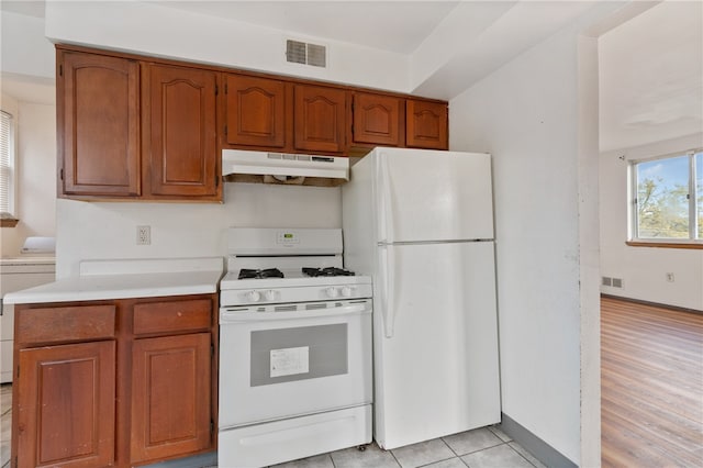 kitchen with white appliances, light wood-type flooring, and washer / clothes dryer