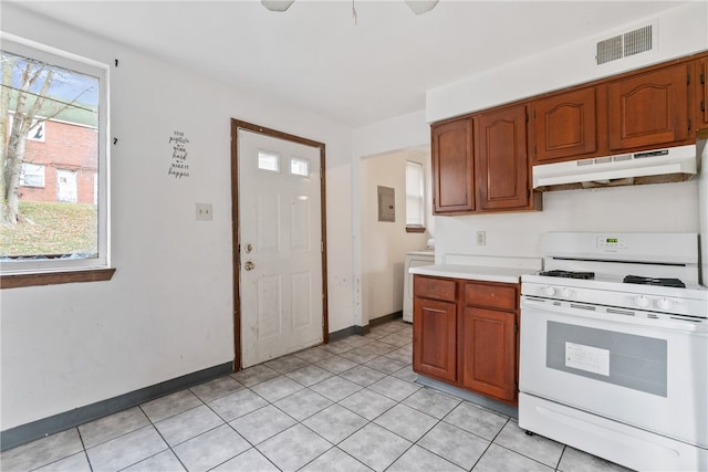 kitchen featuring washer / dryer, light tile patterned floors, and white range with gas cooktop